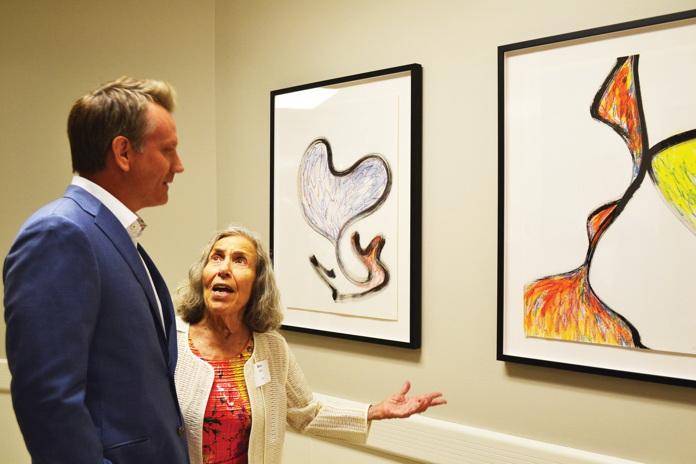 Artist Rita Blitt discusses paintings she donated that are now on display at Menorah Medical Center with the hospital’s CEO Charles Laird.