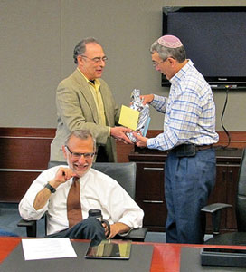 Photo by Marvita Oliver: When the Rabbinical Association met in May, it bid farewell to two rabbis leaving the community — Rabbi Vered Harris and Rabbi Alan Cohen — as well as commemorated Rabbi Herbert J. Mandl’s upcoming retirement. Here Rabbi Mark Levin (left) presents a parting gift to Rabbi Cohen. Seated is Rabbi Avi Weinstein.