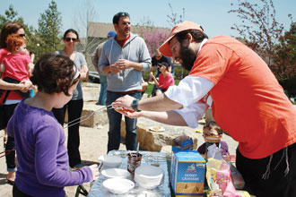 Photo by Rachel Bayer: It was a beautiful day for a picnic Sunday at Gezer Park. Many people who were tired of being cooped up by the cool rainy weather this week showed up for the Communitywide Lag b’Omer celebration sponsored by the Israel Committee of the Jewish Federation of Greater Kansas City, the City of Leawood and the Torah Learning Center. Here Rabbi Simcha Morgenstern helps a young participant make a s’more.