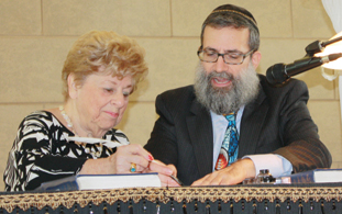 Photo by Rachel Bayer: Eileen Garry, a former president of Congregation Beth Torah, represented the founding members and wrote the first letter in Congregation Beth Torah’s new Torah with assistance from Rabbi Moshe Druin on Oct. 6.